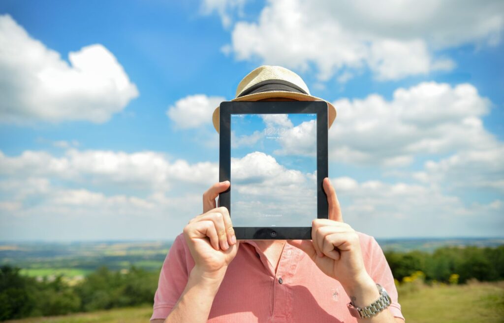 shows someone holding an iPad blended in with the sky - Types of blog posts