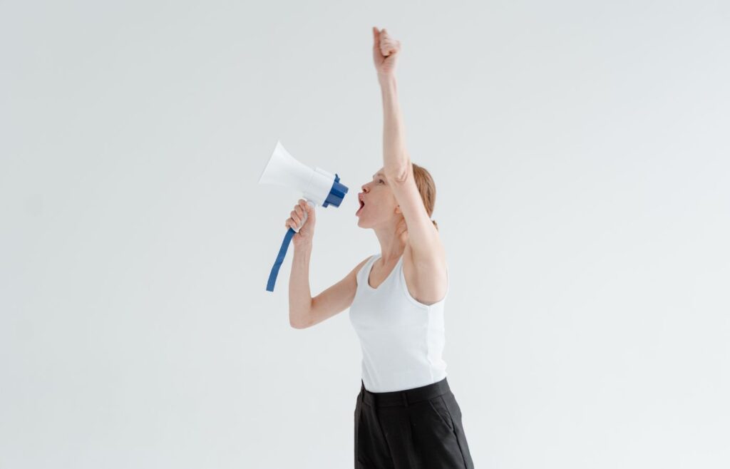 shows a womaan shouting down a megaphone 